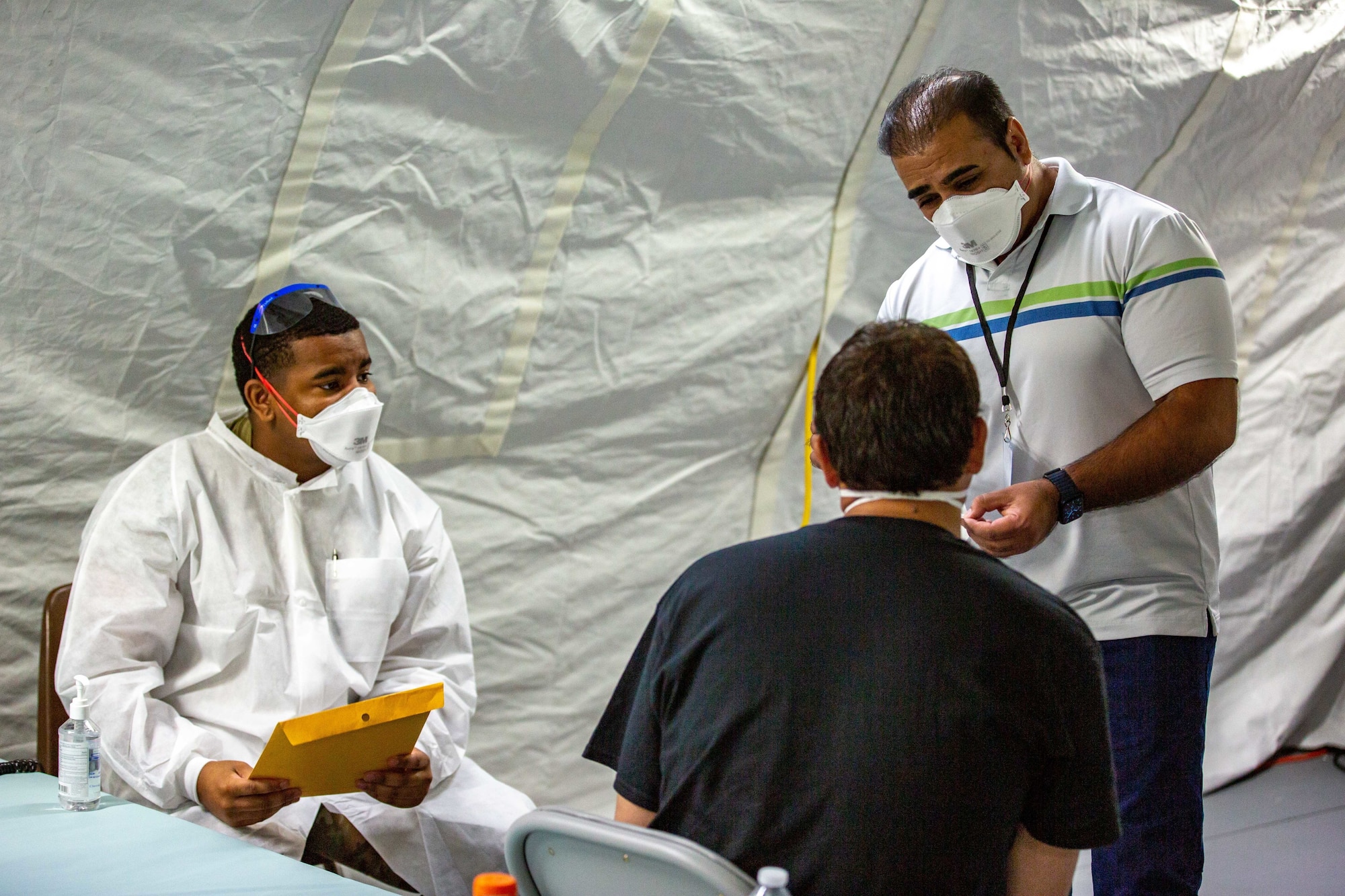 U.S. Air Force Senior Airman Tyler Moore, a medic with the 96th Medical Group (left), and Nasir Elham, an interpreter with the Department of State (right), explains COVID-19 vaccination procedures to an Afghan civilian at a vaccination site in support of Operation Allies Welcome, Fort Pickett, Virginia, Sept. 15, 2021. The Department of Defense, through U.S. Northern Command, and in support of the Department of Homeland Security, is providing transportation, temporary housing, medical screening, and general support for at least 50,000 Afghan evacuees at suitable facilities, in permanent or temporary structures, as quickly as possible. This initiative provides Afghan personnel essential support at secure locations outside Afghanistan. (U.S. Marine Corps photo by Cpl. Eric Ramirez)