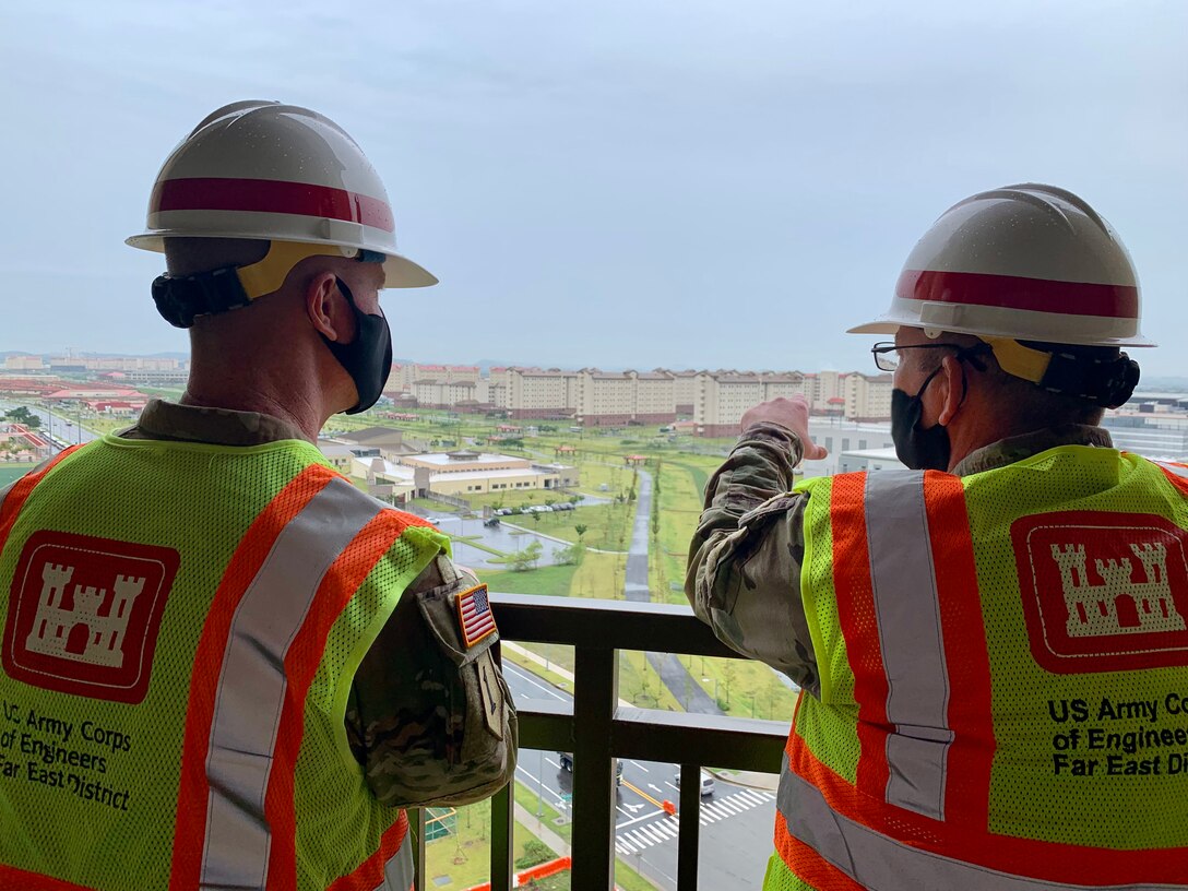 Brig. Gen. Kirk Gibbs (left), U.S. Army Corps of Engineers Pacific Ocean Division commander, listens to Col. Christopher Crary (right), Far East District commander, as they look from the balcony of the newly constructed Army Family Housing Towers at USAG Humphreys, Aug. 25.