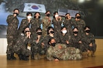 Group photo of 2 U.S. and 10 Korea female soldiers on stage posing for a photo.