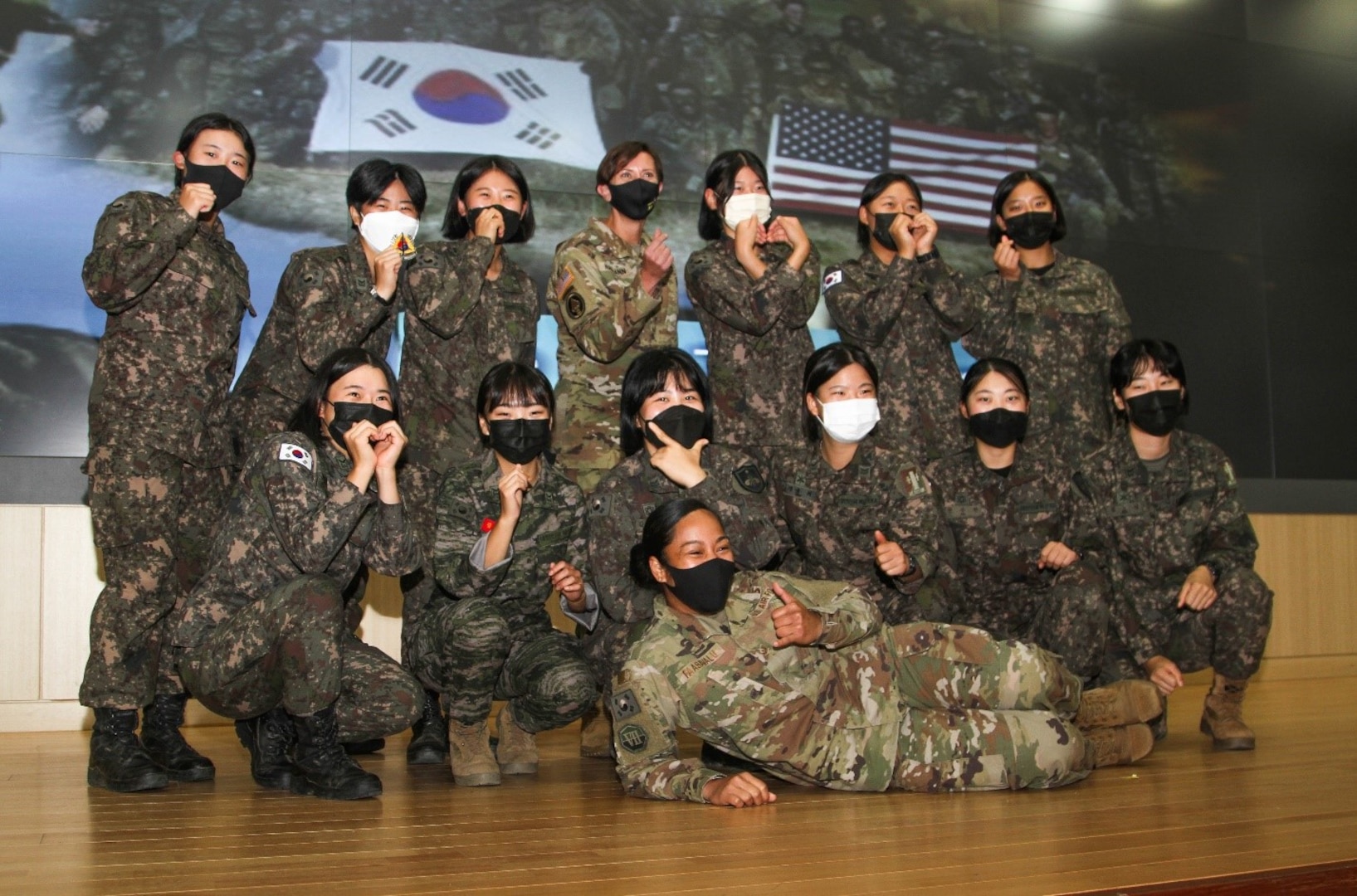 Group photo of 2 U.S. and 10 Korea female soldiers on stage posing for a photo.