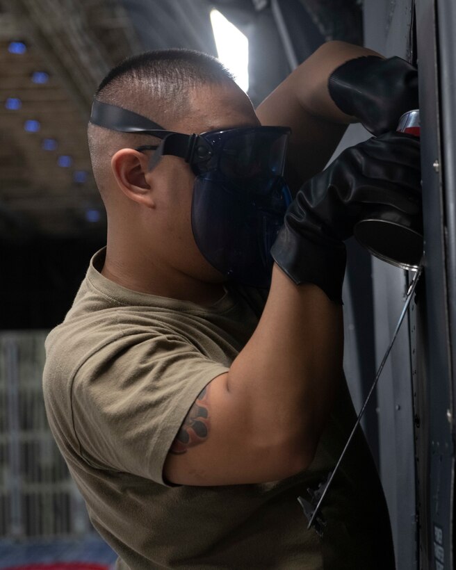 Senior Airman Joe Devera-Cruz, 730th Air Mobility Squadron aircraft maintenance journeyman, pours hydraulic fluid into a C-5M Super Galaxy at Yokota Air Base, Japan, Sept. 15, 2021. Devera-Cruz learned how to fill and drain hydraulic fluid during a familiarization training session. (U.S. Air Force photo by Staff Sgt. Joshua Edwards)