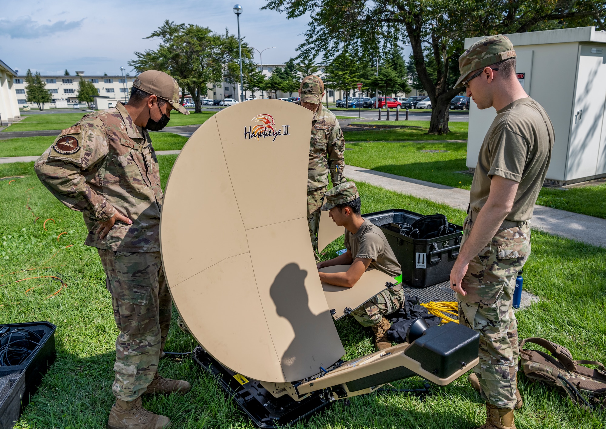 Uniformed people assemble a collapsible satellite dish.