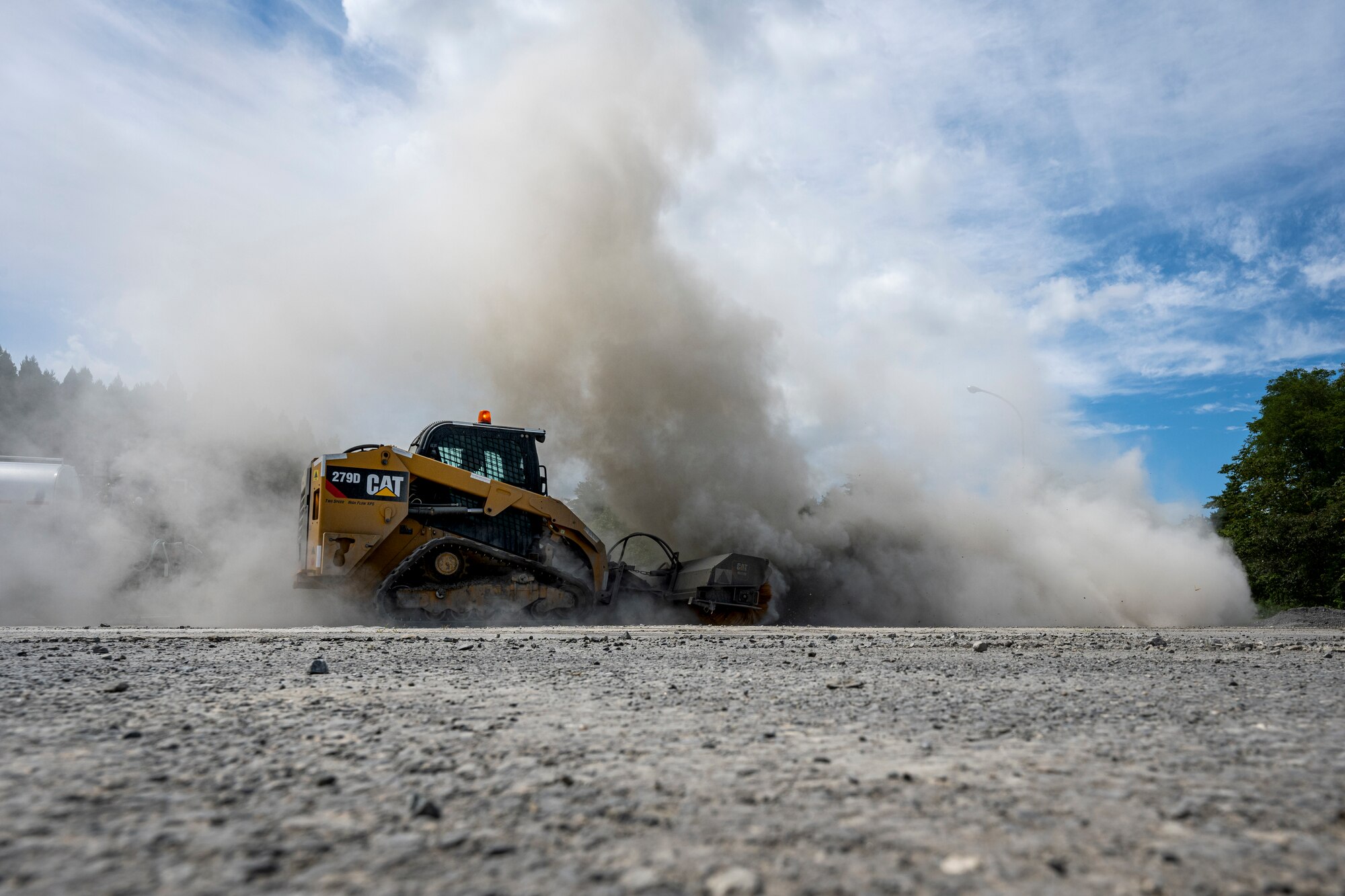 A piece of heavy machinery kicks up a cloud of dust.
