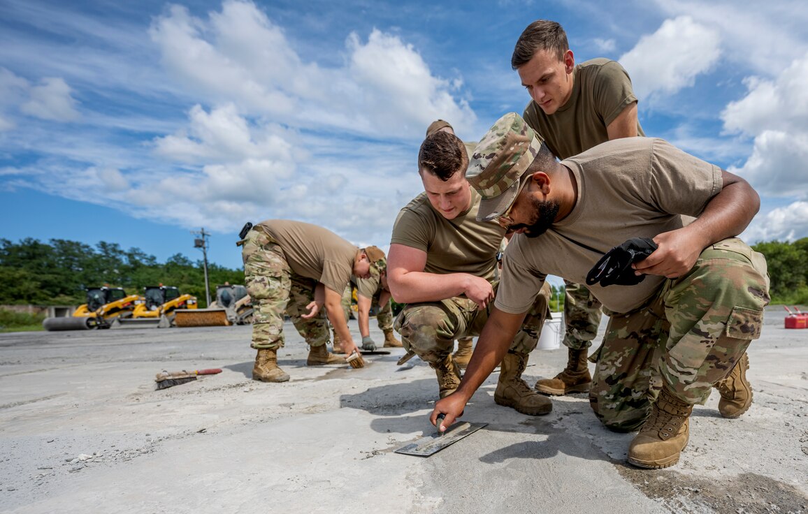 People in uniform smooth wet cement under a blue sky.
