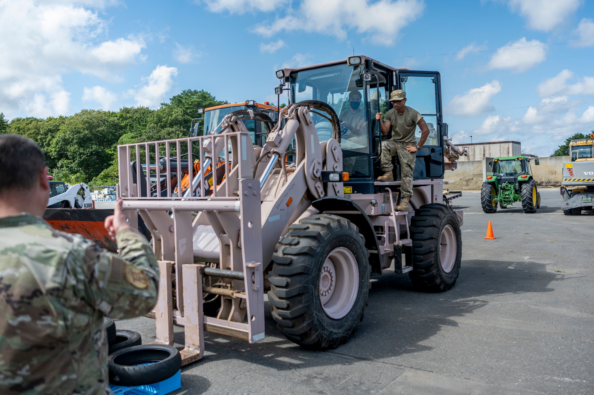 People in uniform operate a large forklift.