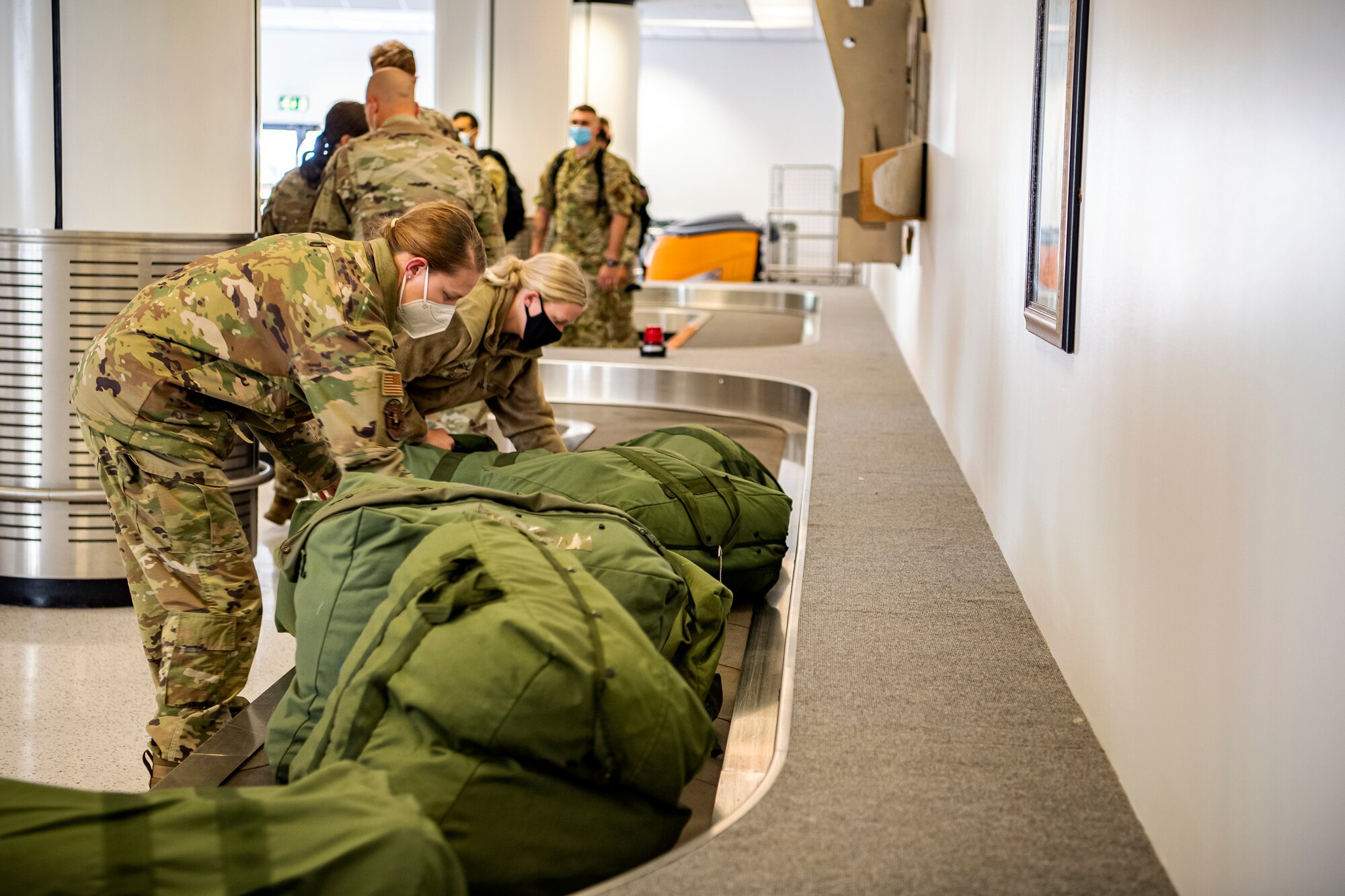 Airmen from the 501st Combat Support Wing, 48th Fighter Wing and 100th Air Refueling Wing, grab their bags in the passenger terminal at RAF Mildenhall, England, Sept. 16, 2021. Defenders from the 501st CSW, 48th FW and 100th ARW returned from Ramstein Air Force Base, Germany, after providing support for Operation Allies Refuge. (U.S. Air Force photo by Senior Airman Eugene Oliver)