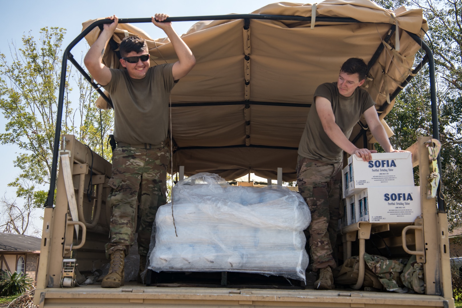 Oklahoma National Guard Spcs. Michael West, left, and Gage Stone, truck drivers with Alpha Company, 120th Engineer Battalion, 90th Troop Command, distribute water, ice and food to those affected by Hurricane Ida in LaPlace, Louisiana, Sept. 7, 2021. Oklahoma National Guardsmen drove throughout neighborhoods to distribute supplies directly to residents.