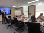 Man speaking to a group of people at a conference table.