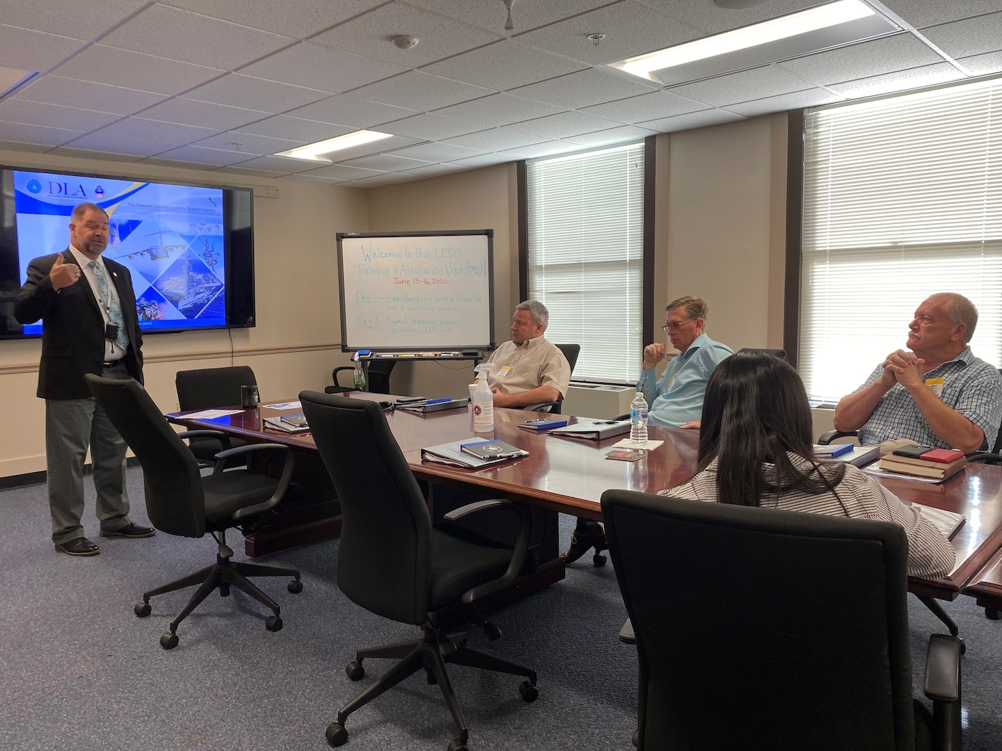 Man speaking to a group of people at a conference table.