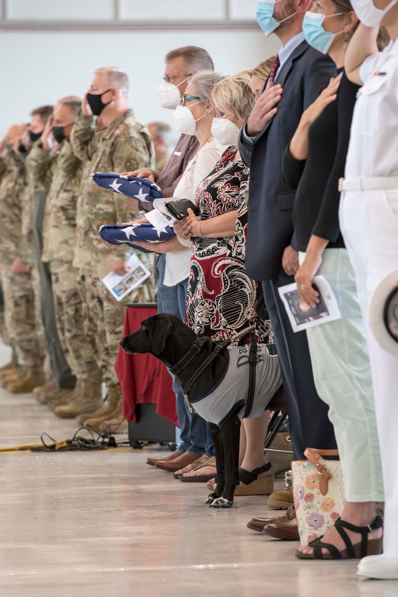 Friends and family of Lt. Col. Barry Rowekamp, including Rowekamp’s dog, Suz, and West Virginia National Guard and 167th Airlift Wing leadership stand for the playing of Taps during a memorial service to honor Rowekamp at the 167th Airlift Wing, Martinsburg, West Virginia, Aug. 19, 2021. Rowekamp was the 167th AW’s chief of aerospace medicine. (U.S. Air National Guard photo by Senior Master Sgt. Emily Beightol-Deyerle)