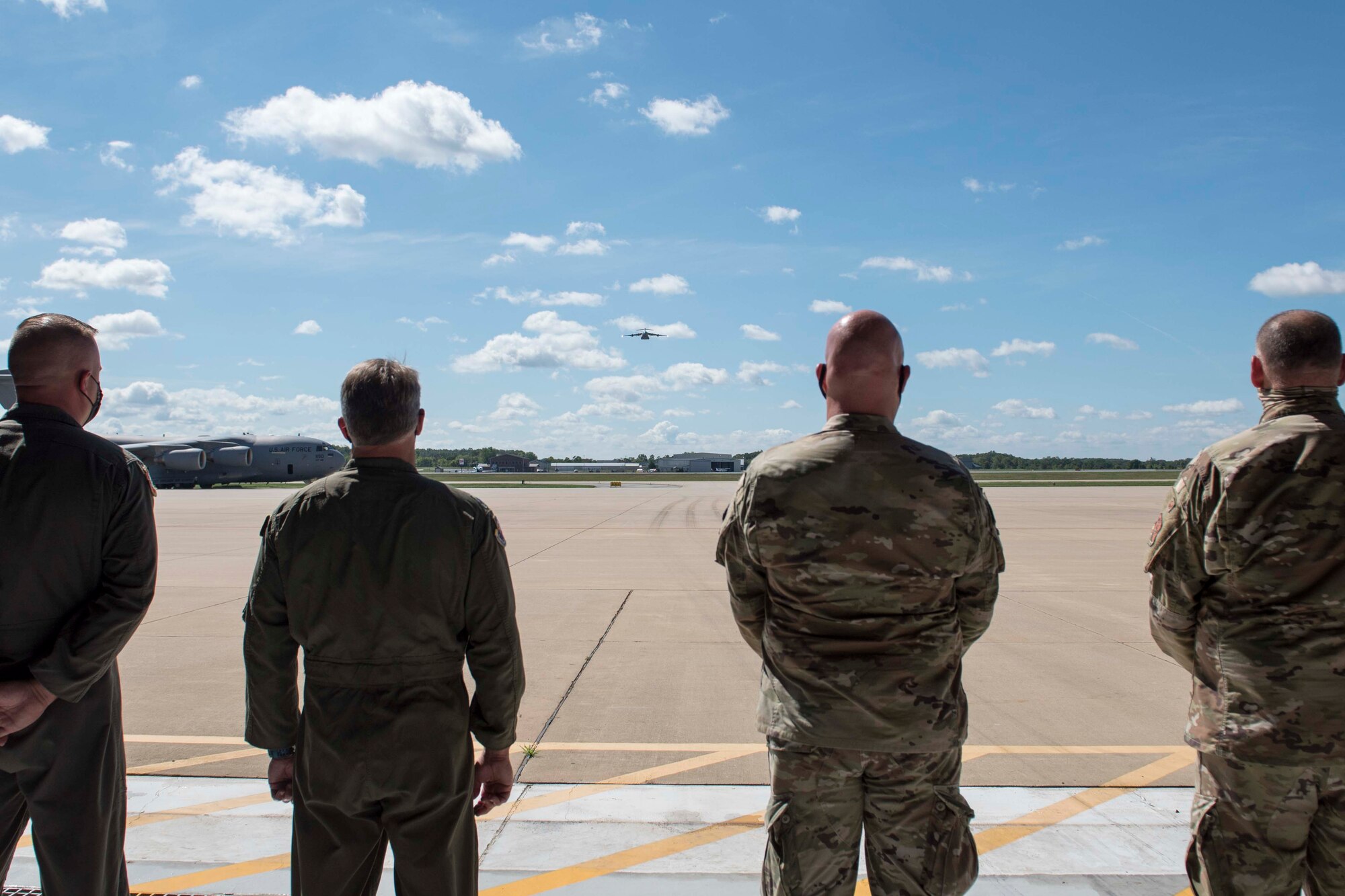 Members of the 167th Airlift Wing watch as a C-17 Globemaster III aircraft approaches Shepherd Field, Martinsburg, West Virginia, for a flyover at the conclusion of the memorial service for Lt. Col. Barry Rowekamp, Aug. 19, 2021. Rowekamp was the wing’s chief of aerospace medicine. (U.S. Air National Guard photo by Senior Master Sgt. Emily Beightol-Deyerle)