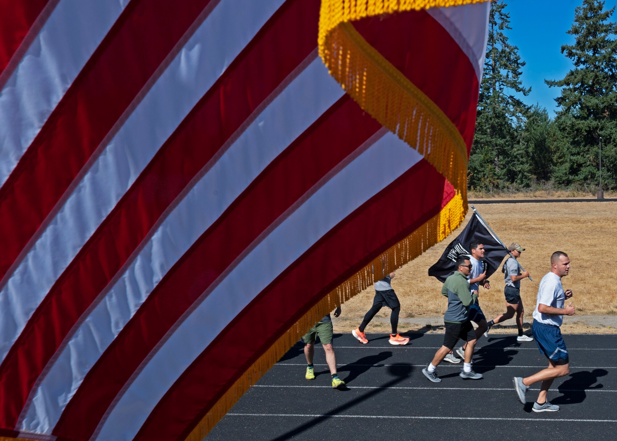 U.S. Airmen with the 627th Civil Engineer Squadron run with the POW/MIA flag during the 24-hour remembrance run at Joint Base Lewis-McChord, Washington, Sept. 16, 2021. Collectively, Team McChord ran more than 300 miles to honor the sacrifice and memory of those Americans who were prisoners of war or were, and may still be, missing in action. (U.S. Air Force photo by Senior Airman Zoe Thacker)