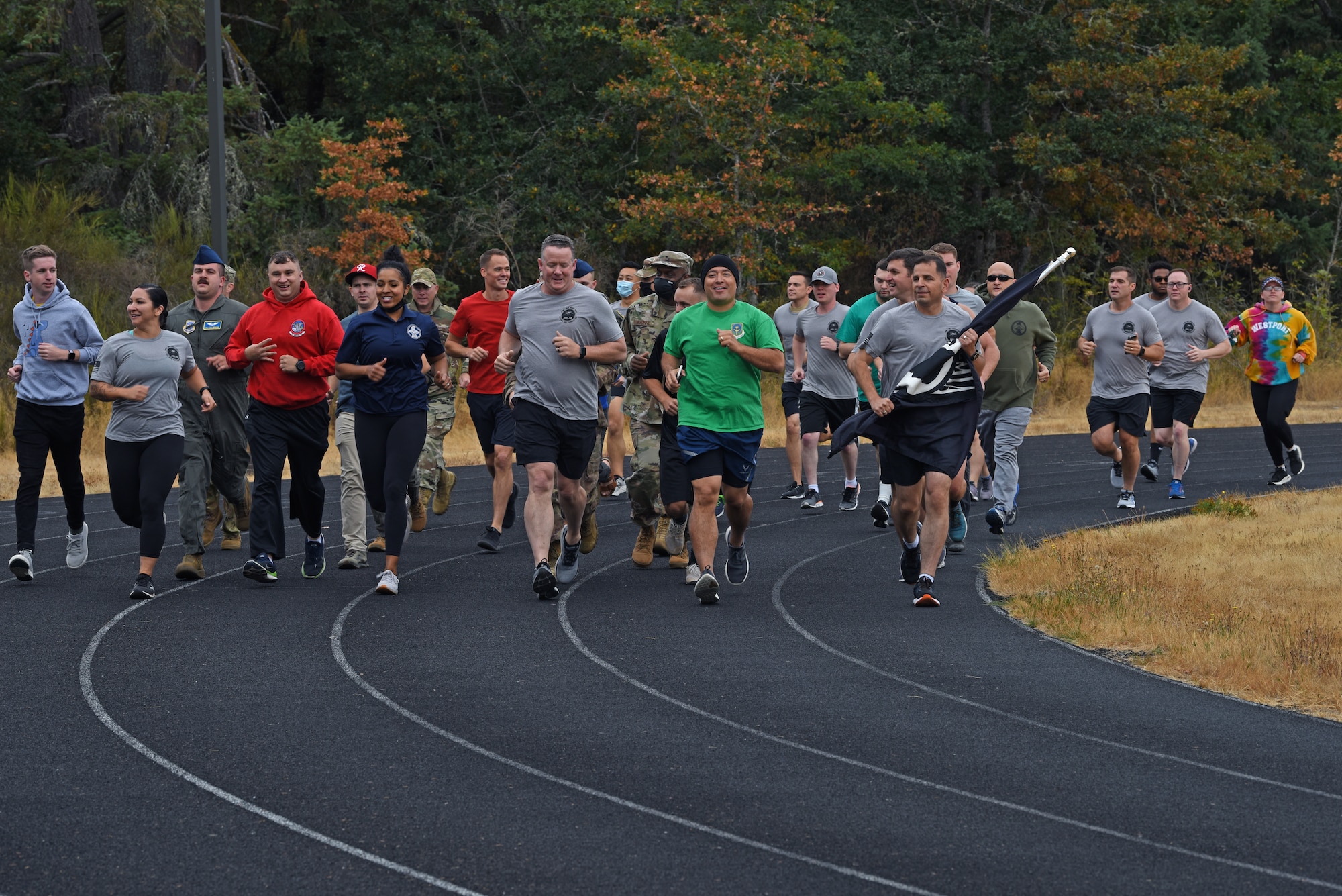 U.S. Airmen with the 62nd Airlift Wing participate in a 24-hour POW/MIA Remembrance Run on the McChord Field track at Joint Base Lewis-McChord, Washington, Sept. 15. 2021. The flag which they carried, the official U.S. POW/MIA flag, was created through the efforts of family members of POW/MIA Americans to display a suitable symbol that made the public aware of their loved ones who were being held prisoner or declared missing during the Vietnam War. (U.S. Air Force photo by Senior Airman Zoe Thacker)