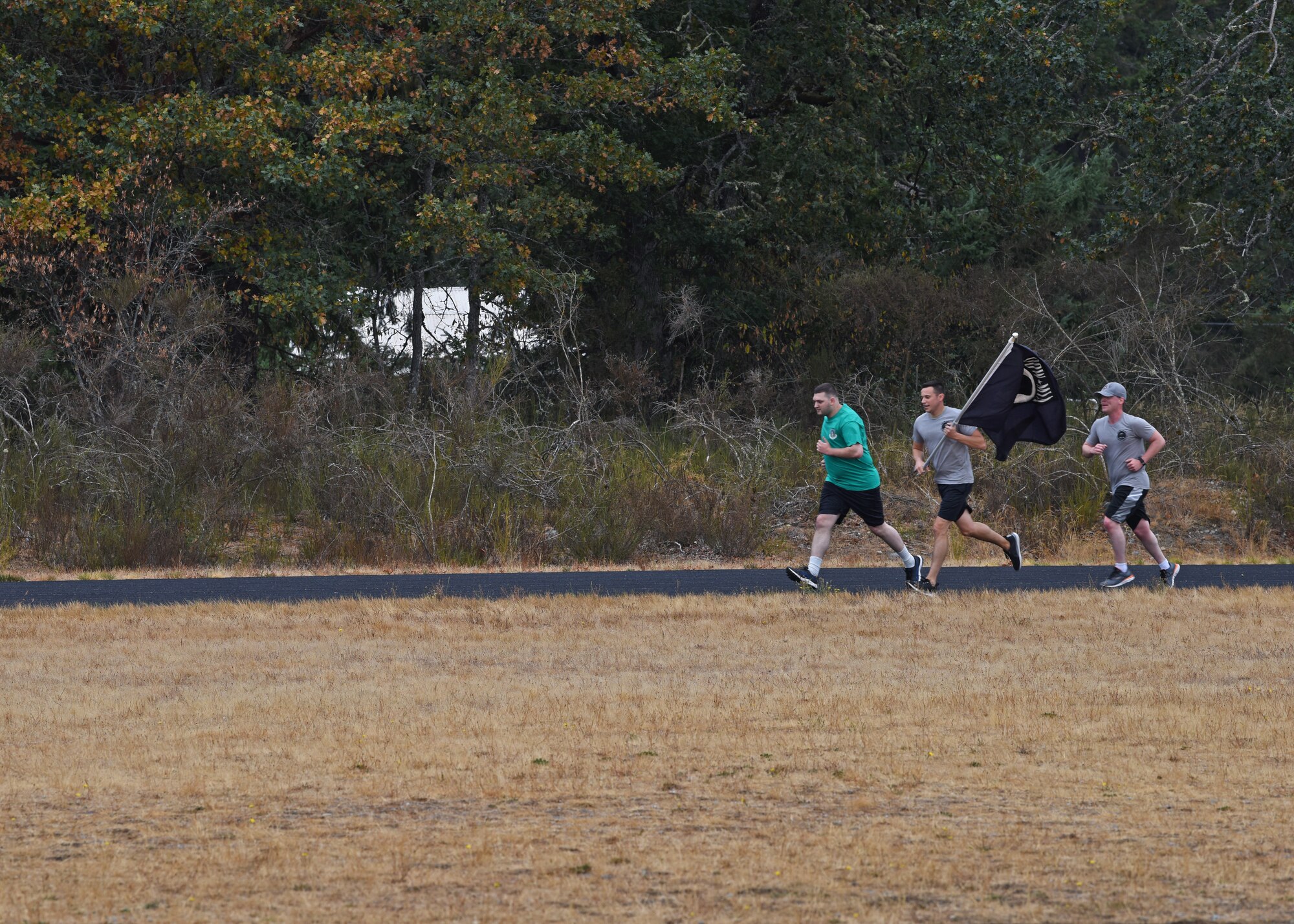 U.S. Airmen with the 62nd Comptroller Squadron carry the POW/MIA flag on the McChord Field track while participating in the 24-hour POW/MIA Remembrance Run at Joint Base Lewis-McChord, Washington, Sept. 15, 2021. Team McChord planned several events this week to honor the lives and sacrifices of those men and women who were prisoners of war or missing in action, including a Missing Man Table and Honors Ceremony, a community motorcycle ride and a wreath laying ceremony. (U.S. Air Force photo by Senior Airman Zoe Thacker)