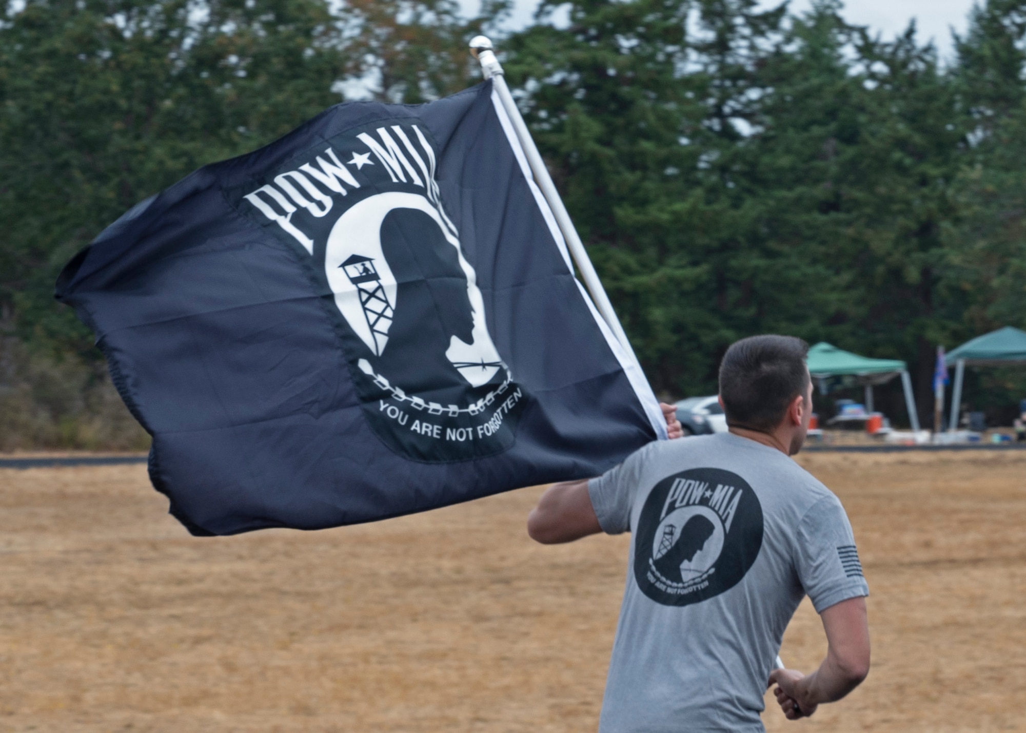 U.S. Air Force Senior Master Sgt. Daniel Cain, 62nd Comptroller Squadron superintendent, runs with the POW/MIA flag during a 24-hour remembrance run at Joint Base Lewis-McChord, Washington, Sept. 15, 2021. Team McChord planned several events this week to honor the lives and sacrifices of those men and women who were prisoners of war or missing in action, including a Missing Man Table and Honors Ceremony, a community motorcycle ride and a wreath laying ceremony. (U.S. Air Force photo by Senior Airman Zoe Thacker)