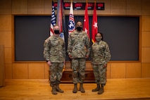 three people wearing army uniforms pose for a photo.