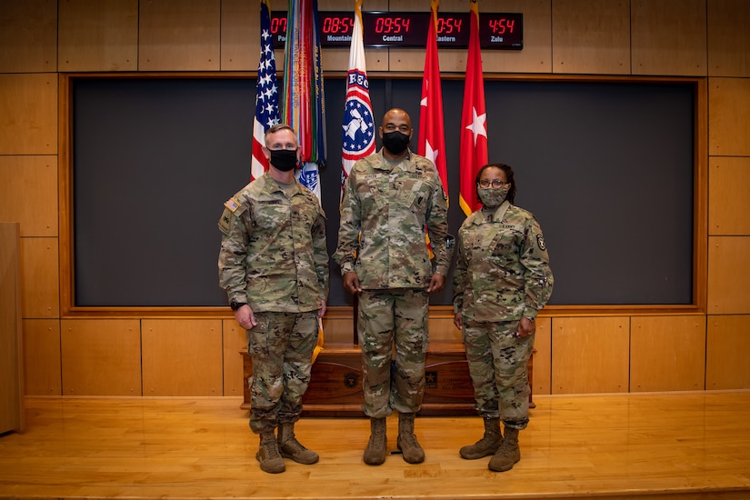 three people wearing army uniforms pose for a photo.