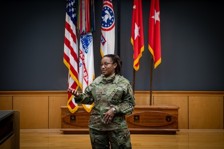 Woman wearing an army uniform standing in the middle of a room.