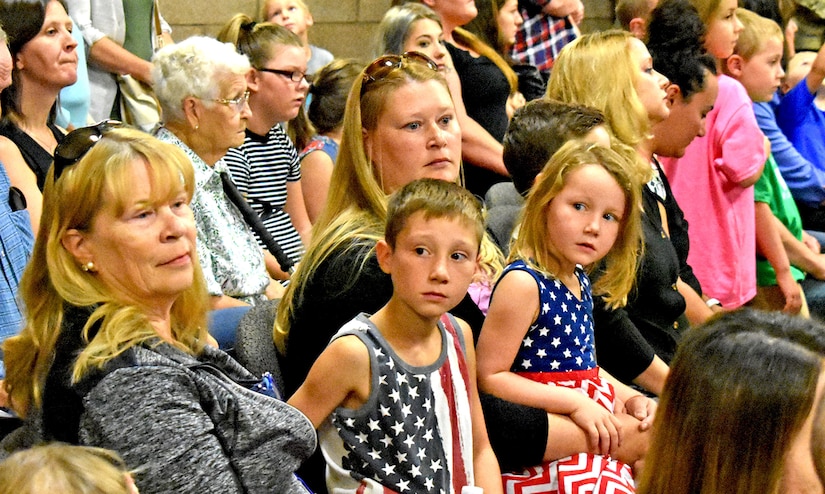 Children and adults are seated in a room.