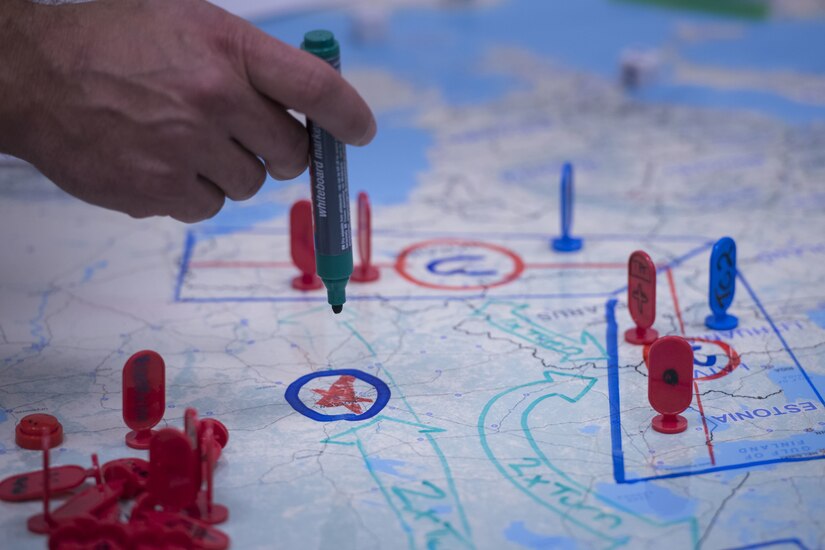 A hand holds a marker above a map.