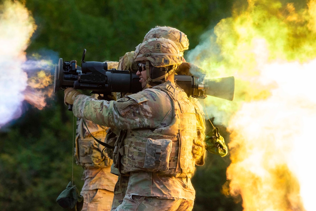 A soldier fires an over the shoulder weapon as smoke and flames surround.