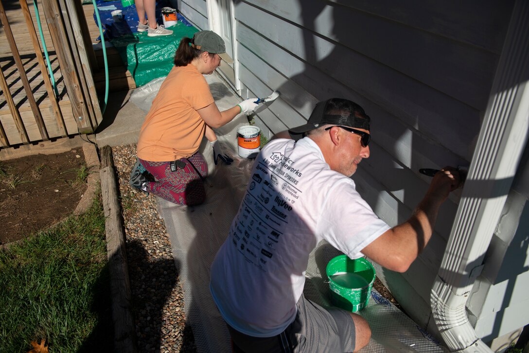 Michelle Butler (top), contract specialist,U.S. Army Corps of Engineers, Omaha District, Environmental Remediation Division, and Adam Ashton, special projects project manager, USACE Omaha District, paint the side of the house during the 2021 Paint-A-Thon, Aug. 21, 2021,