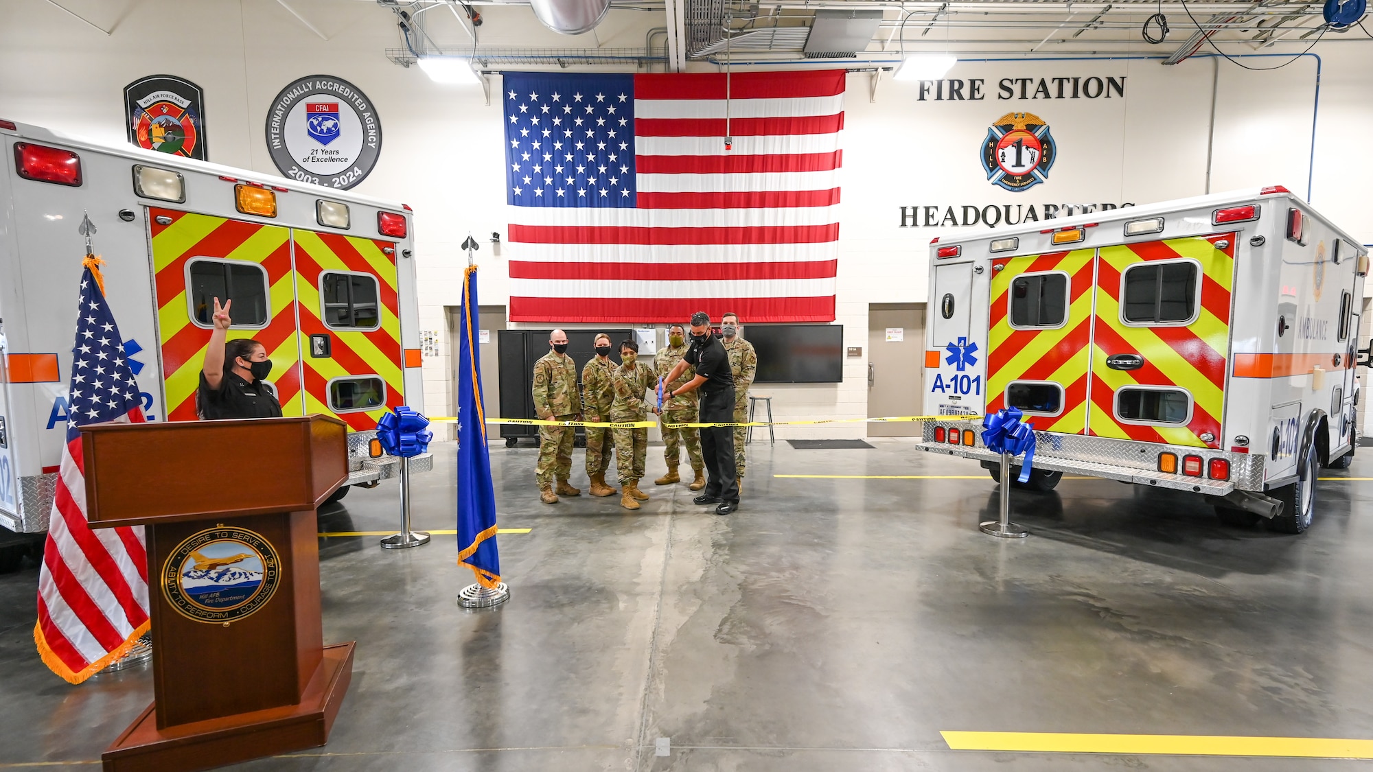 Base officials are flanked by two ambulances as they cut a ribbon.