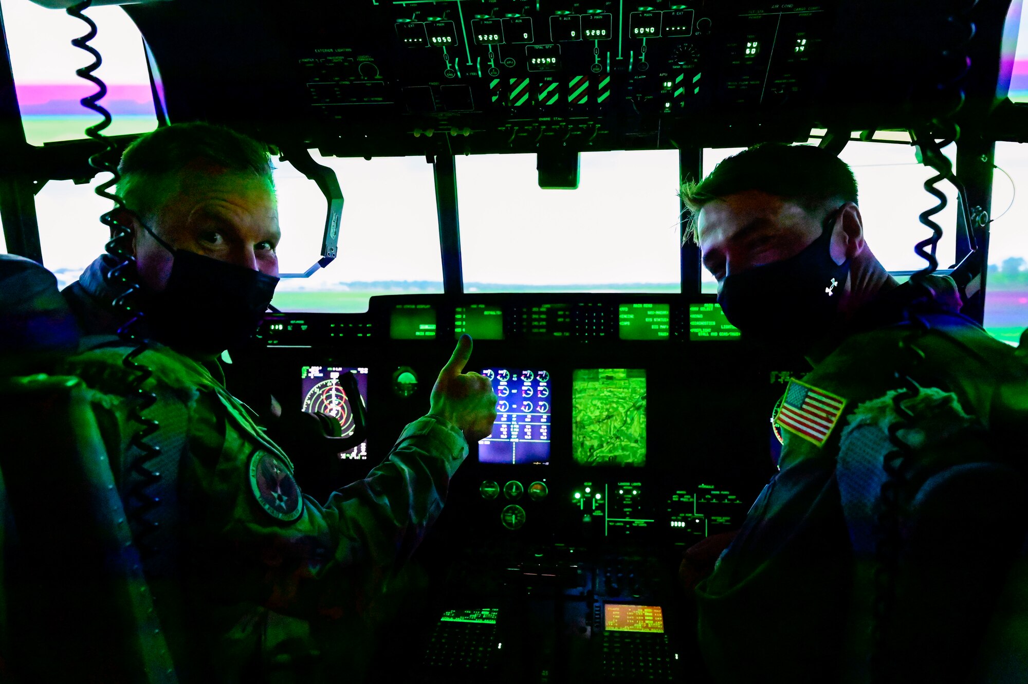 Two people pose for a photo in a C-130 simulator