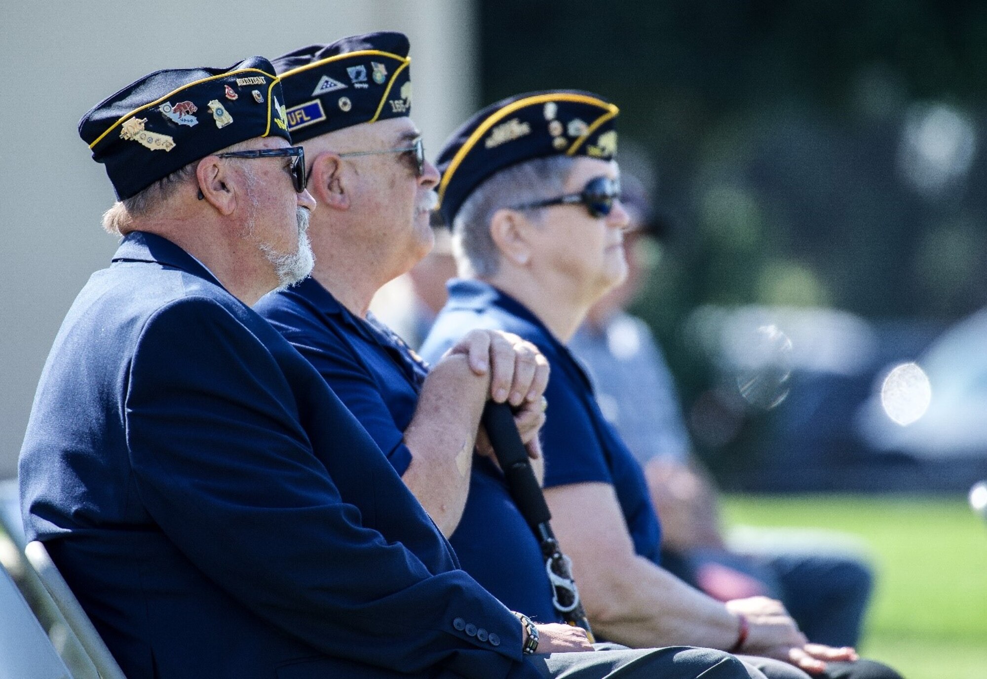 Representatives from VFW posts look to a stage on a sunny day