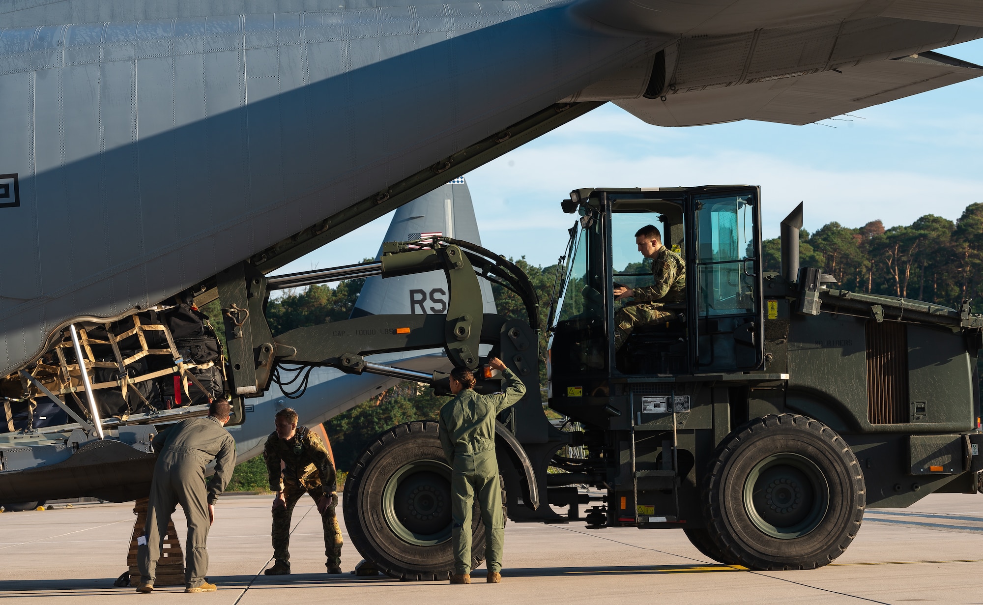 Airmen load cargo on aircraft.