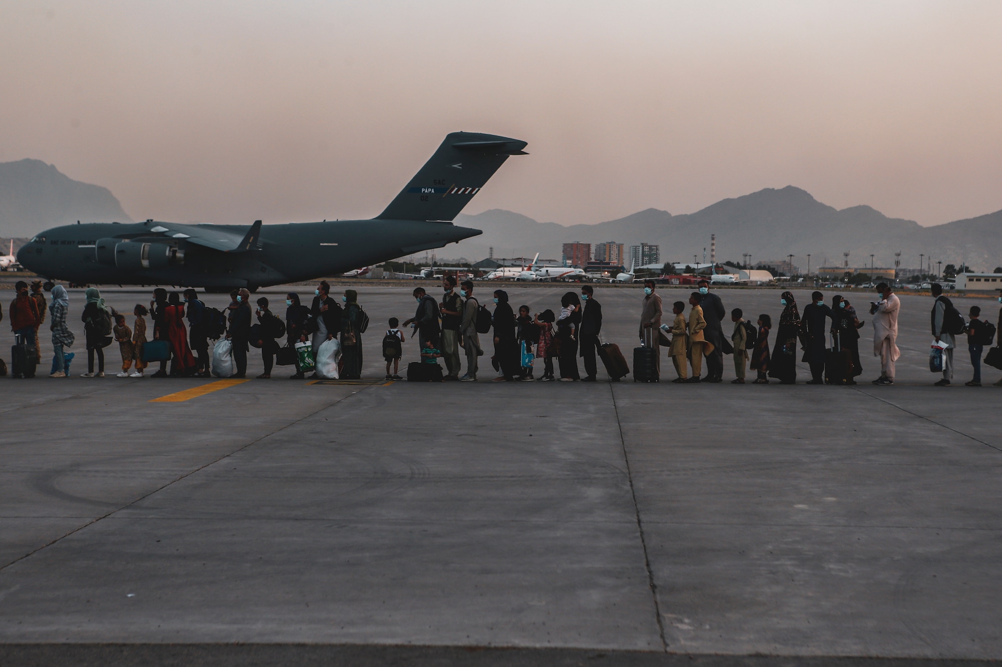 Evacuees wait to board a Boeing C-17 Globemaster III during an evacuation at Hamid Karzai International Airport, Kabul, Afghanistan, Aug. 23. U.S. service members are assisting the Department of State with a Non-combatant Evacuation Operation (NEO) in Afghanistan. (U.S. Marine Corps photo by Sgt. Isaiah Campbell)
