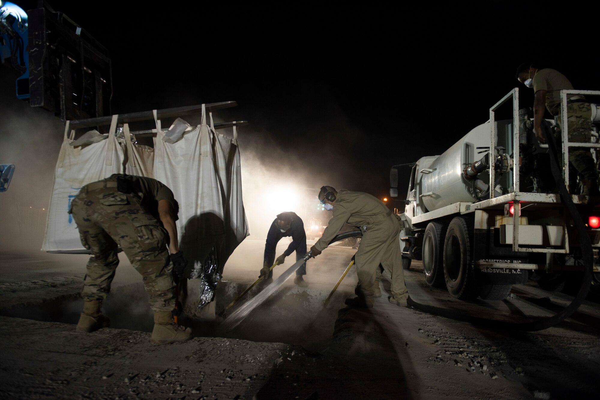 A photo of Airmen pouring water and mixing a solution in a hole