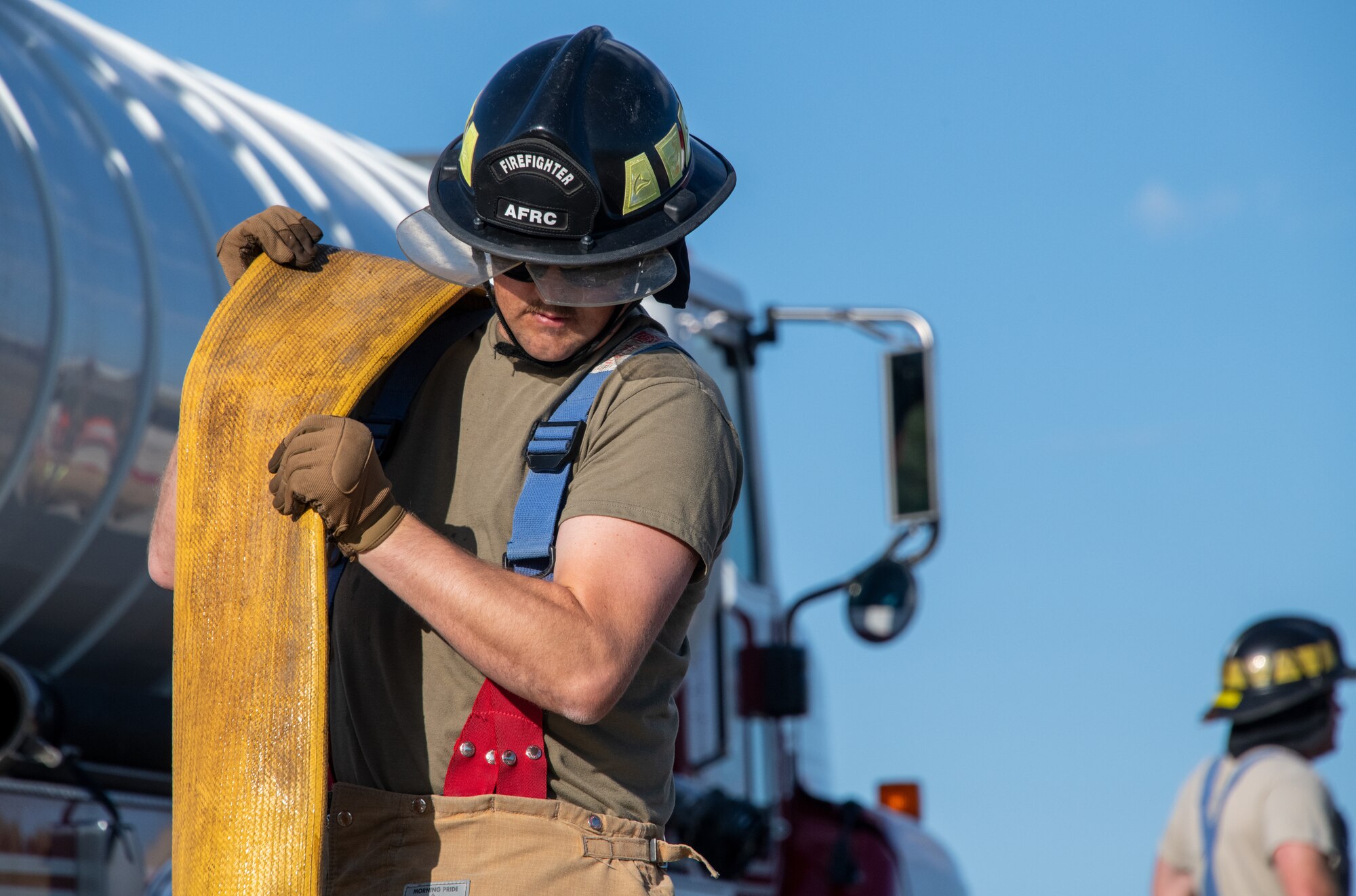 U.S. Air Force Staff Sgt. Nicholas Pittson, firefighter with the 419th Civil Engineer Squadron, carries a firehose after responding to an aircraft live-fire burn