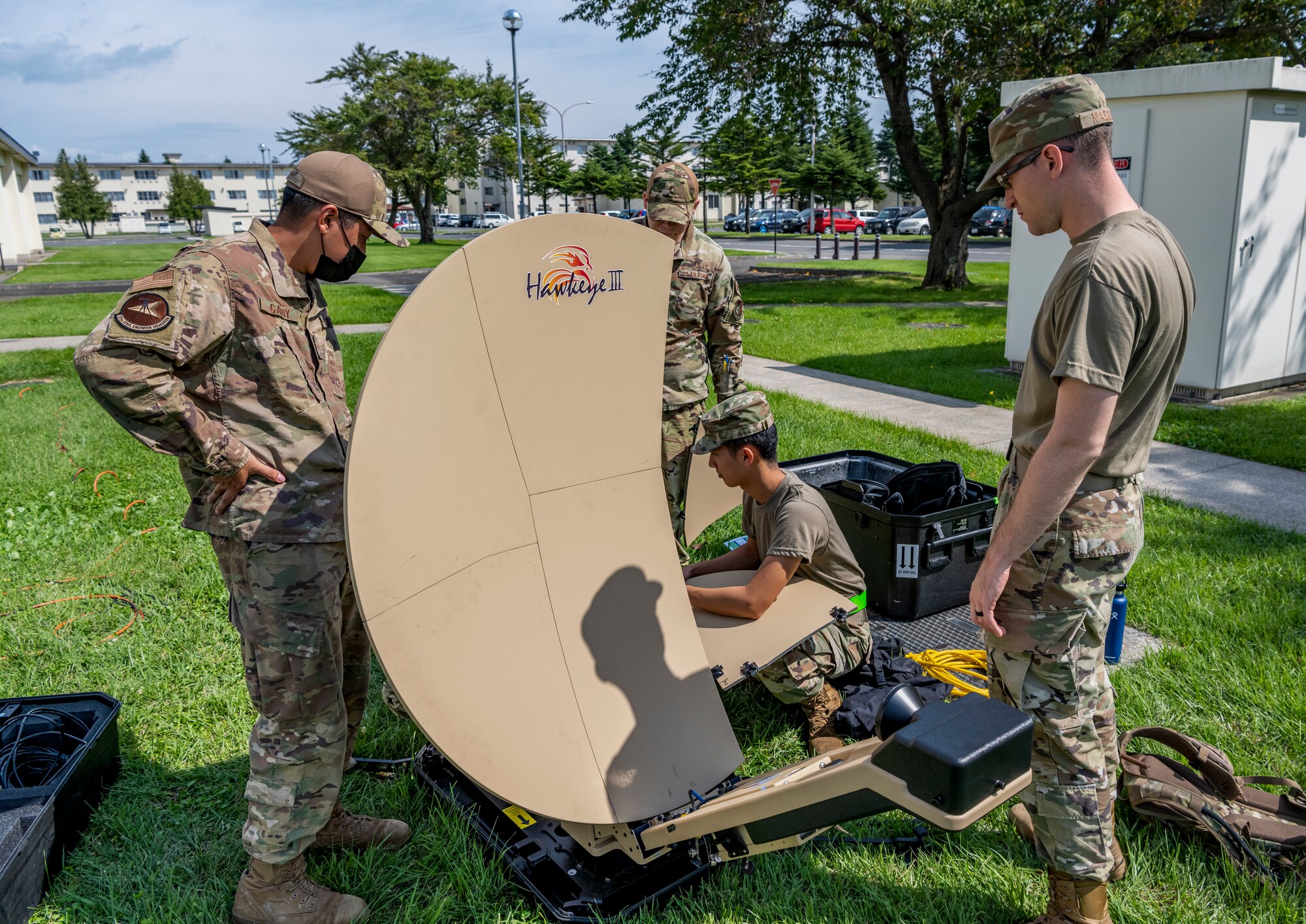 Uniformed people assemble a collapsible satellite dish.