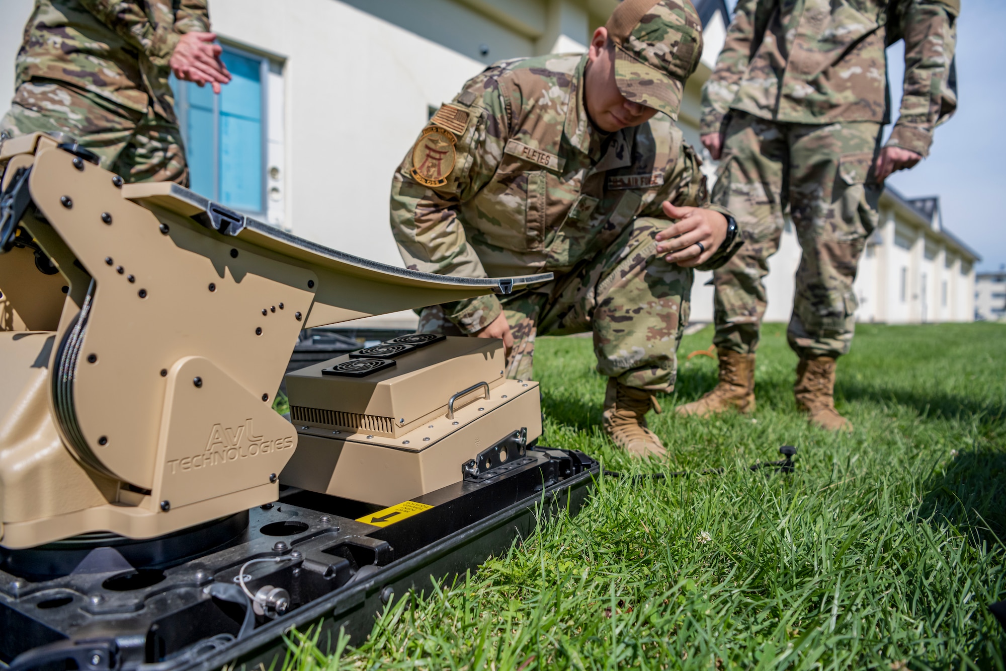 Uniformed personnel look at a disassemble piece of equipment.