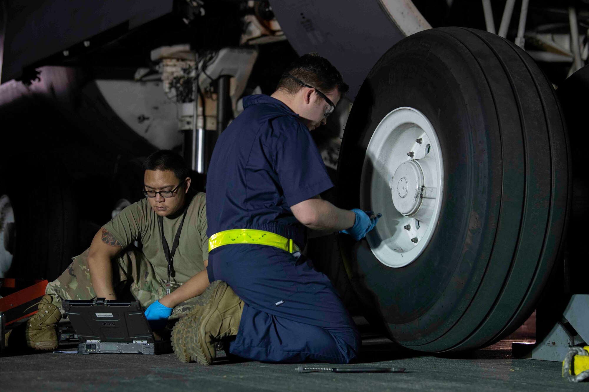 Senior Airmen Joseph Devera-Cruz, left, and Joshua James, right, 730th Air Mobility Squadron aircraft maintenance journeymen, prepare to change a tire on a C-5M Super Galaxy at Yokota Air Base, Japan, Sept. 13, 2021.