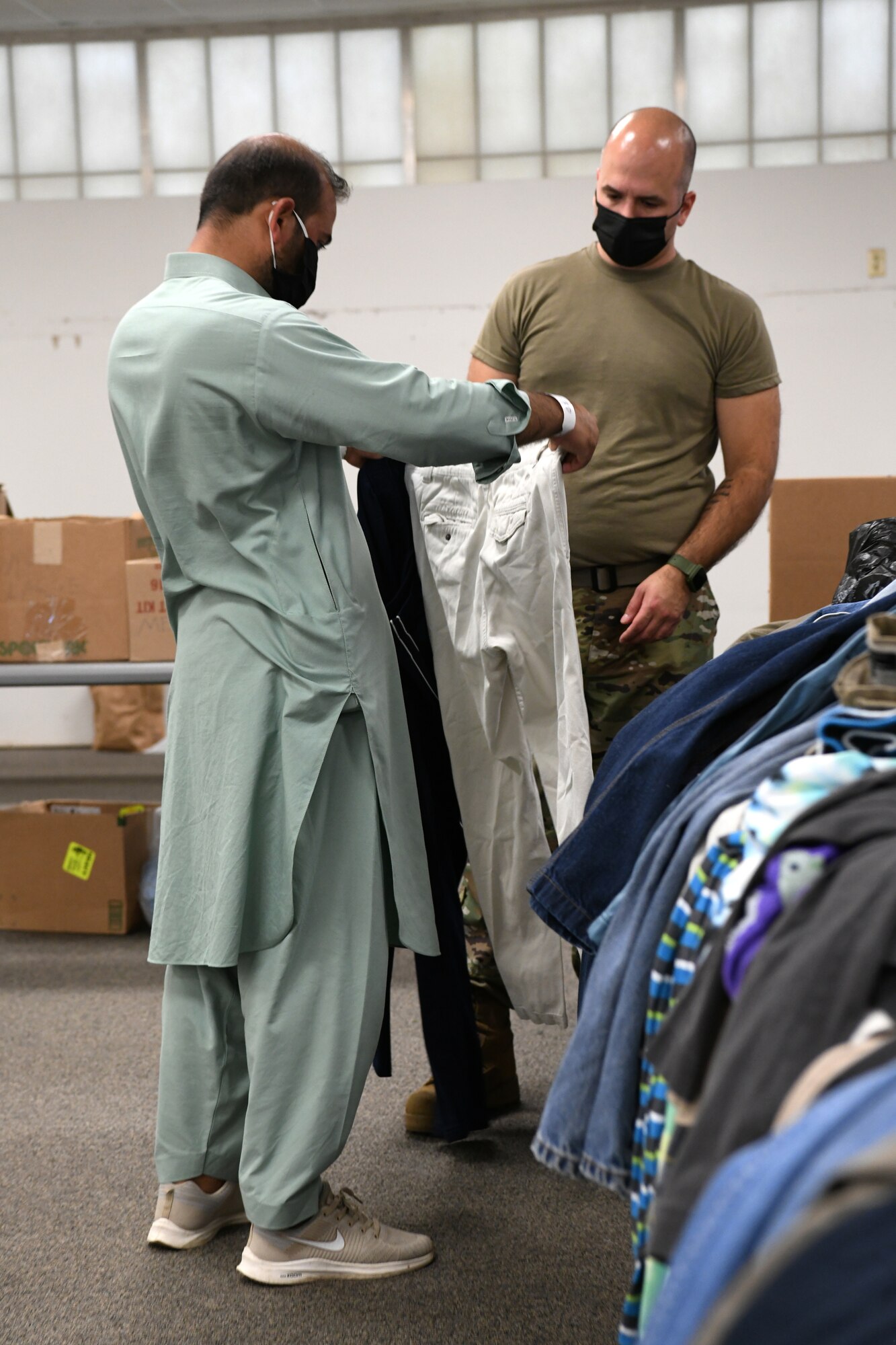 U.S. Air Force Tech. Sgt. Kenneth Brooks, Task Force Liberty personnel from the 143rd Medical Group, Rhode Island, helps an Afghan look for clothing at the Liberty Village, Joint Base McGuire-Dix-Lakehurst, New Jersey, on Sept. 2, 2021. The Department of Defense, through U.S. Northern Command, and in support of the Department of Homeland Security, is providing transportation, temporary housing, medical screening, and general support for at least 50,000 Afghan evacuees at suitable facilities, in permanent or temporary structures, as quickly as possible. This initiative provides Afghan personnel essential support at secure locations outside Afghanistan. (National Guard photo by Master Sgt. John Hughel, Washington Air National Guard)