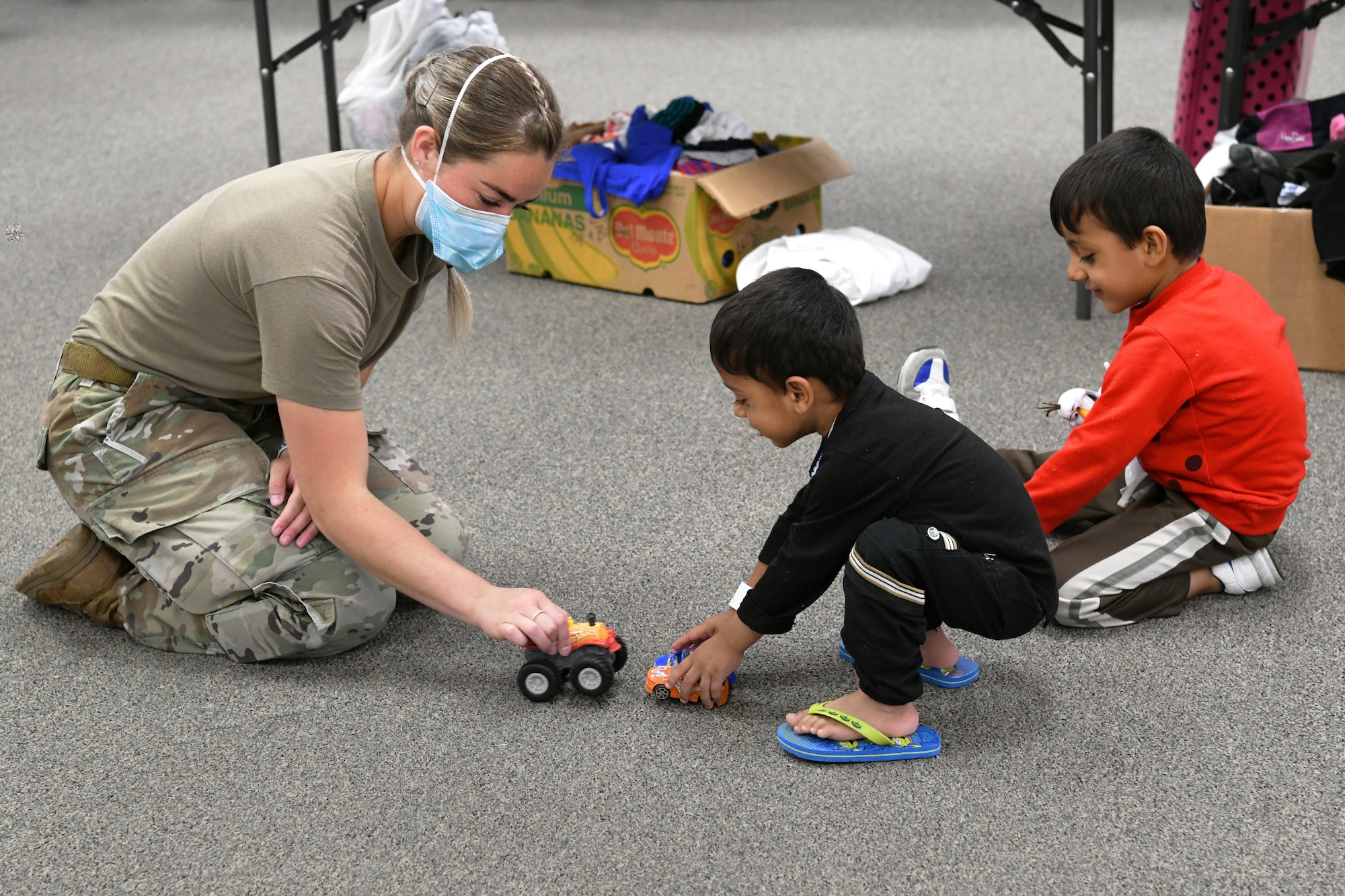 U.S. Air Force Staff Sgt. Jessica Ness, Task Force Liberty personnel from the 316th Security Forces Group, entertains Afghans while their parents look for clothing at Liberty Village on Joint Base McGuire-Dix-Lakehurst, New Jersey, on Sept. 2, 2021. The Department of Defense, through U.S. Northern Command, and in support of the Department of Homeland Security, is providing transportation, temporary housing, medical screening, and general support for at least 50,000 Afghan evacuees at suitable facilities, in permanent or temporary structures, as quickly as possible. This initiative provides Afghan personnel essential support at secure locations outside Afghanistan. (National Guard photo by Master Sgt. John Hughel, Washington Air National Guard)