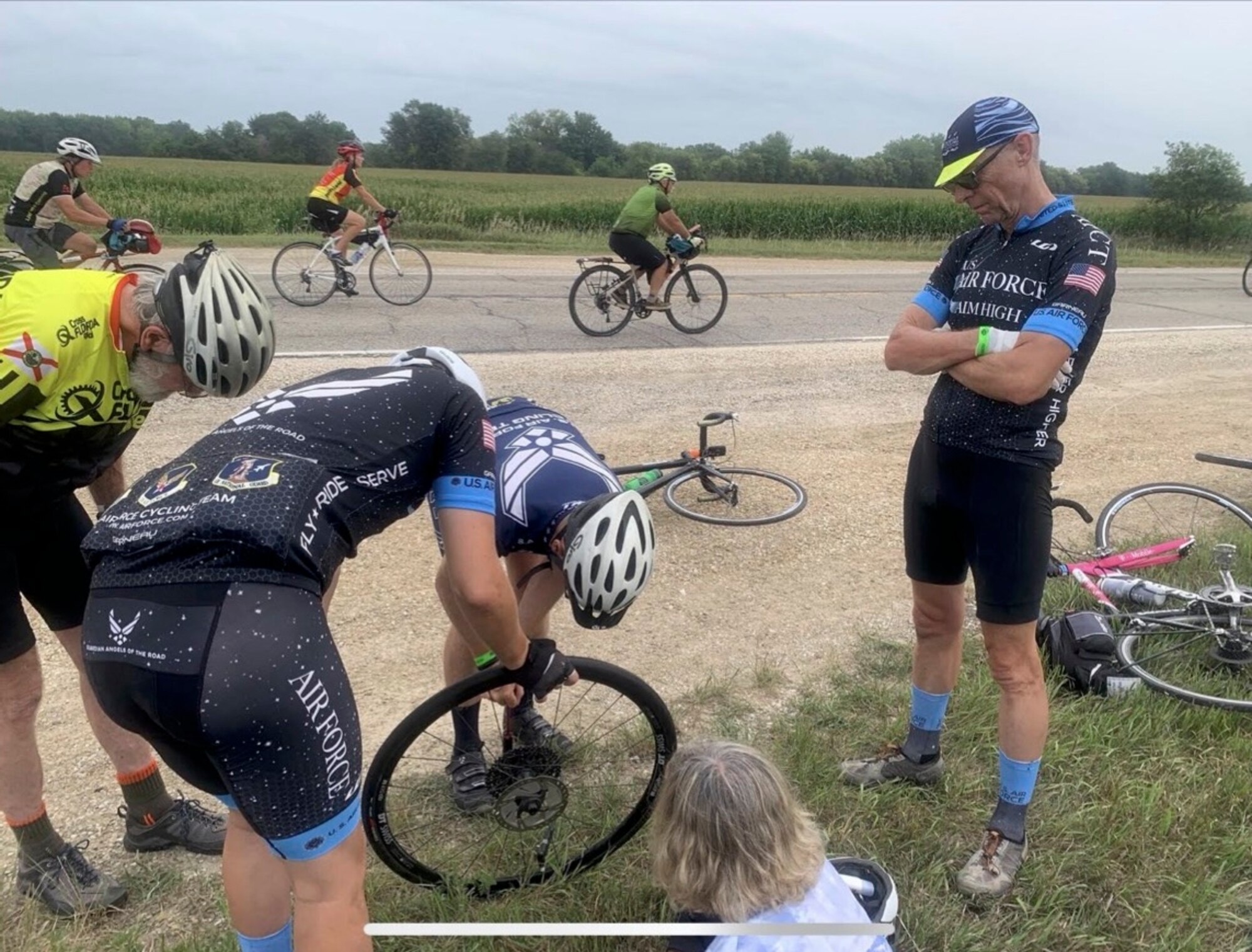 Photo of an Airman helping another AFCT cyclist fix a bike tire in Iowa.