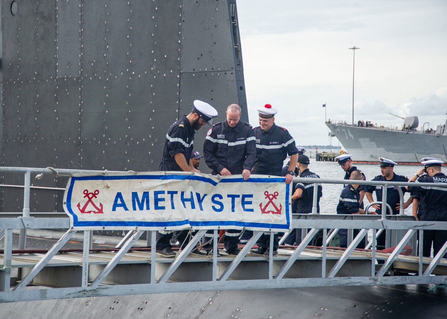 Crewmembers assigned to the French submarine FNS Améthyste (S605) place the boat’s banner as it moors pier side at Naval Station Norfolk, Sept. 16, 2021.