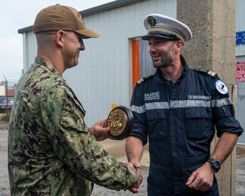 Lt. Cmdr. Jeff Vandenengel, the executive officer assigned to the Virginia-class fast-attack submarine USS John Warner (SSN 785), exchange gifts with Cmdr. Aymeric Schaeffer, the commanding officer of the nuclear-powered French submarine FNS Amethyste (S605), at Naval Station Norfolk, Sept. 17, 2021.