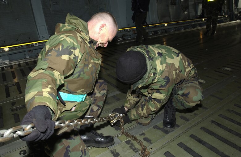 US Air Force (USAF) Master Sergeant (MSGT) Stephen Hartmaier, Communication Specialist, 621st Air Mobility Operations Group (AMOG), uses Tie-Down Chains to secure a MARC (Mobility Air Reporting Center), 621st AMOG, McGuire Air Force Base (AFB), New Jersey (NJ), to the deck of the C-5 Galaxy. The C-5 will fly troops and equipment to a CENTCOM (US Central Command) Area of Responsibility (AOR) in support of Operation ENDURING FREEDOM.