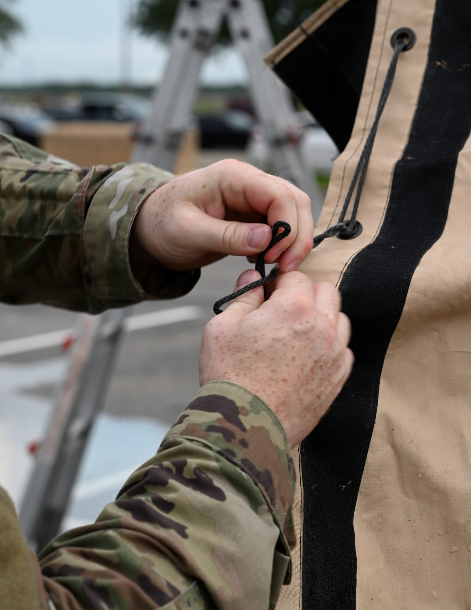 a member ties a tent rope in a knot