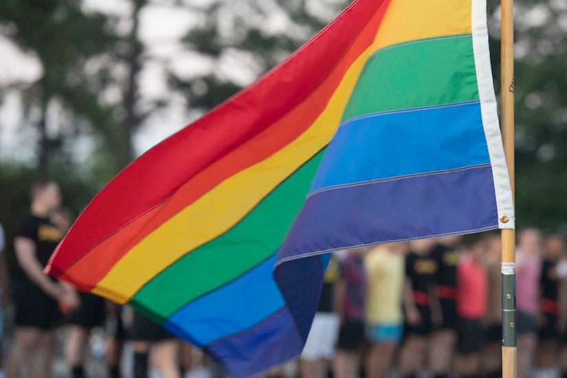 A colorful flag flies; a crowd is in the background.