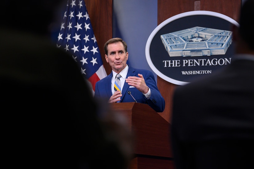 Civilian speaks while standing at a lectern to a seated audience.