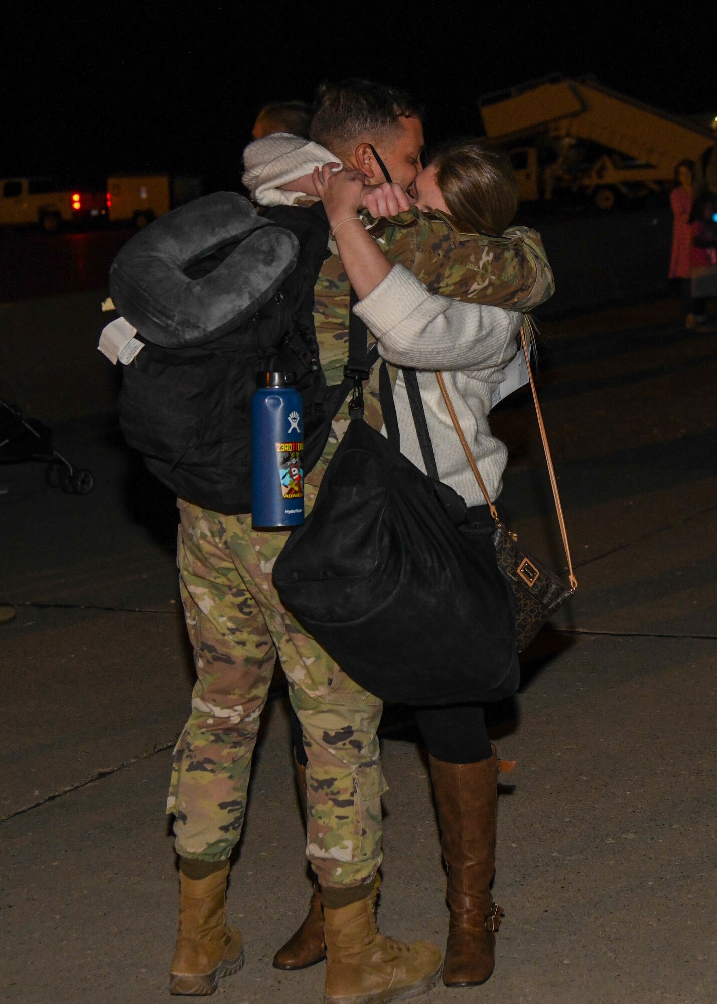 A spouse hugs her spouse as he returns from deployment