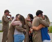 spouses hug their loved ones as they return from deployment