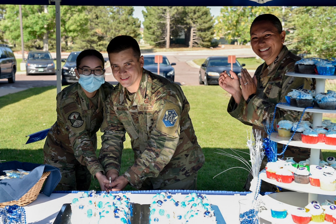 Peterson leadership and an Airman cut the air force birthday cake with a saber.