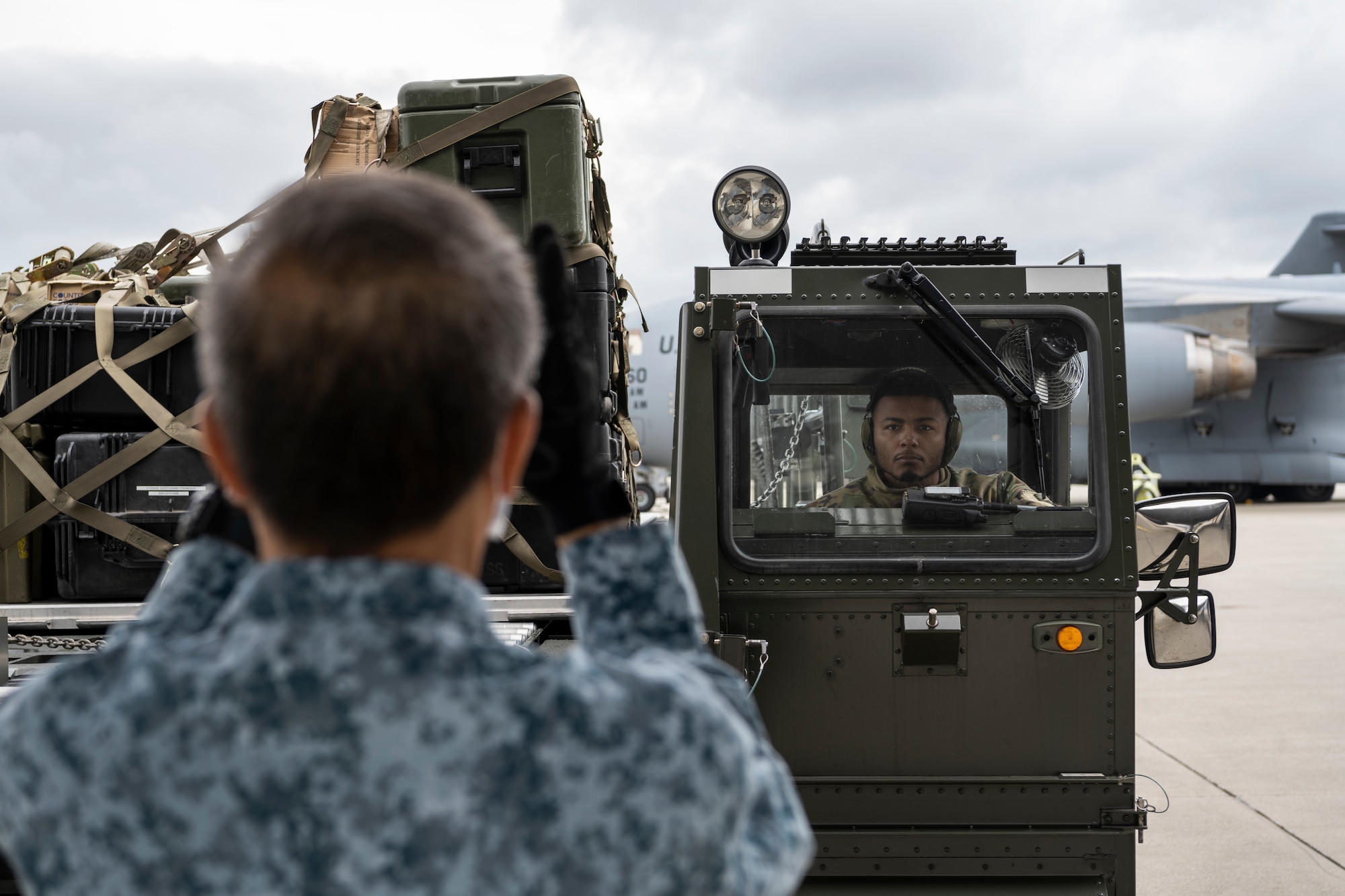 A Republic of Singapore Air Force personnel guides U.S. Air Force Staff Sgt. Jordan Gilchrist, 726th Air Mobility Squadron aircraft services supervisor, as he operates a Tunner 60K aircraft cargo loader on Spangdahlem Air Base, Germany, Aug. 29, 2021.