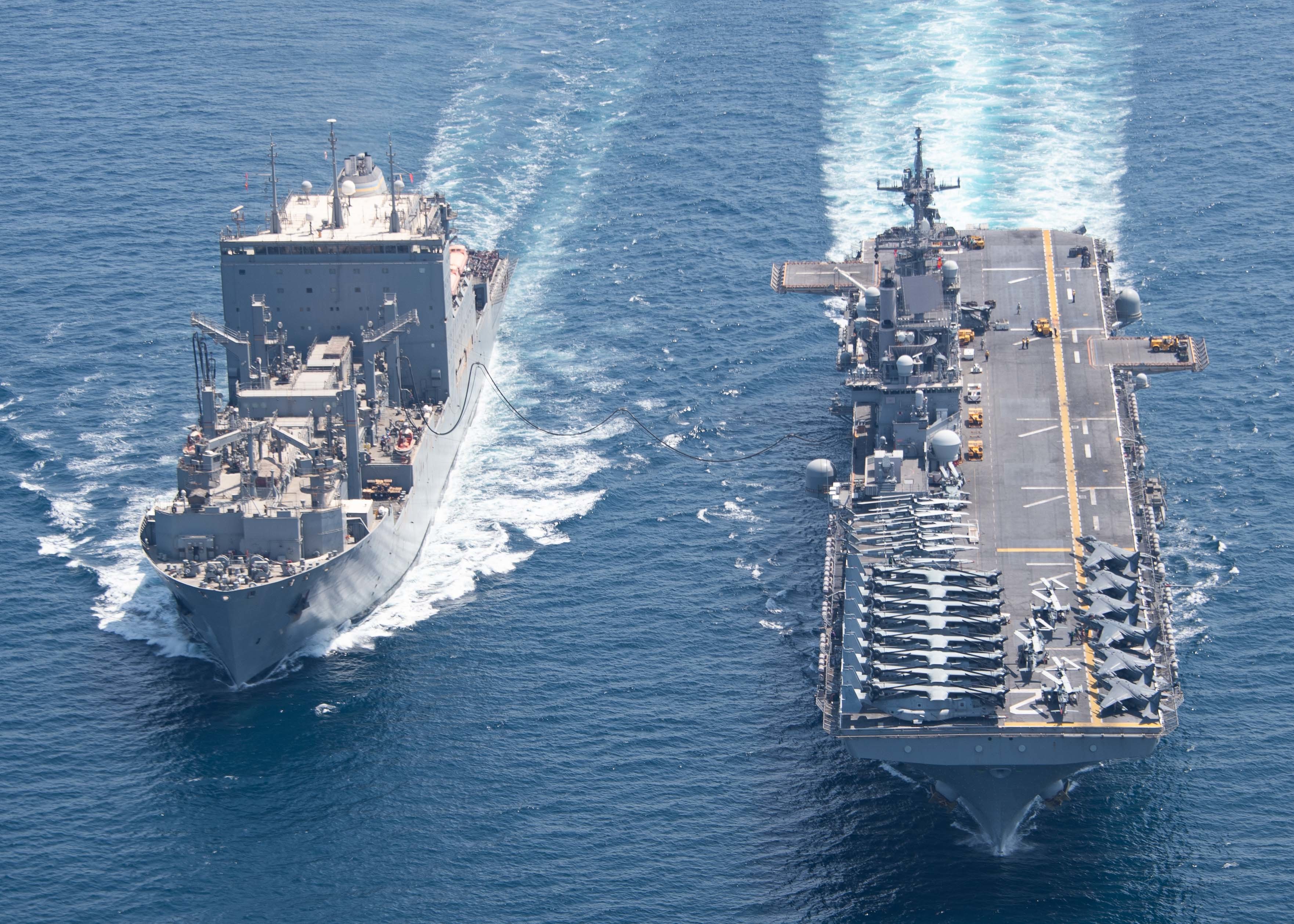 The dry cargo and ammunition ship USNS Wally Schirra (T-AKE 8), left, conducts a replenishment-at-sea with the amphibious assault ship USS Essex (LHD 2), right, Sept. 18, 2021.